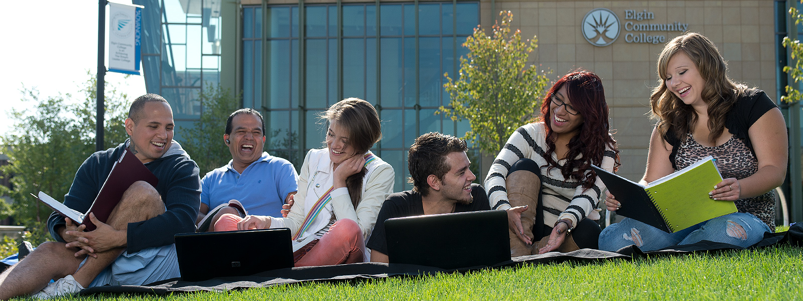Students that are enjoying sitting on lawn in front of Building C.